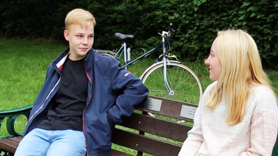 two young people talking on a bench